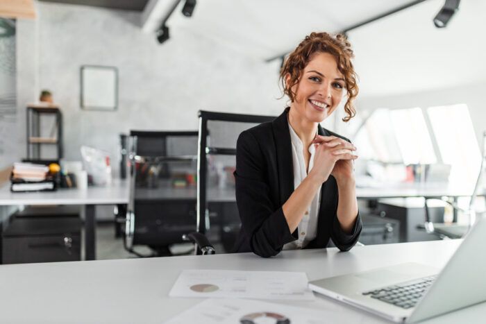 Portrait of a happy manager at bright office. Smiling at camera while sitting at office desk.